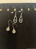 Two pairs of dangling earrings on display card