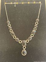 Full view of silver-tone necklace with black faceted stones and drop pendant