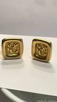 Front view of both square gold-tone clip-on earrings showing textured centers