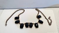 Full view of brass-tone necklace with seven black faceted stones