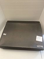 Closed black Kenneth Cole Reaction shoebox with white label and lot number sticker.