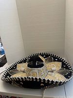 Black velvet sombrero showcasing gold floral embroidery, sequins, and braided trim.