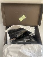 Black leather Florsheim men's dress shoes displayed inside a brown box with tissue paper.