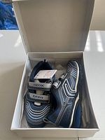 Pair of navy and royal blue Geox J Bernie B kids shoes in open shoe box showing velcro straps and shoe details