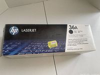 Closed box of HP LaserJet 36A black toner cartridge showing product details and slight box creasing.