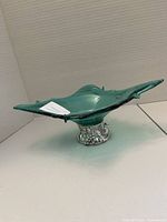 Side profile of green/teal Italian art glass bowl showing shape, handles, and clear textured base.