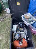 Open black wheeled case containing assorted tools, an orange bag with bulbs, plastic bin with hardware, and power tools.