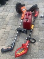 Photo showing two string trimmers and a red gas can arranged on pavement, displaying handles and guards clearly.