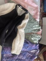 Various girls' jackets including black and white sherpa fleece, light green quilted, purple patterned, and pink item