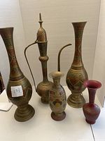 Front view of all five brass vessels showing various sizes and etched designs in metallic colors