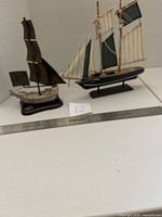 Pair of wood and metal ship models on bases with a ruler for scale