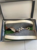 Pair of Tommy Hilfiger casual shoes inside the box showing dark gray fabric upper and white soles