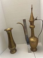 Front view of the pair showing the heights and details. The ewer with a handle and lid is taller and the vase is shorter and flared at the top. Both have etched floral designs.