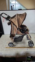 Full side view of tan and black pet stroller with ruler for scale