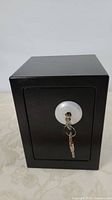 Front view of closed black safe with key inserted