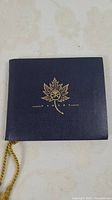 Closed navy album with gold maple leaf crest