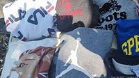 Six sweatshirts laid out showing Fila, Raptors, Roots, lion graphic, Jordan, Springfield