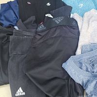 Pile of assorted gym clothes showing Adidas tights, Gymshark top, Champion sweatshirt