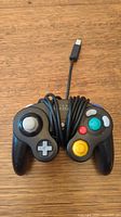 Front of black GameCube controller with buttons and wrapped cable
