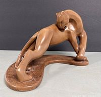 Side view of the hand painted ceramic panther sculpture showing the stretch pose on textured base.