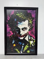 Framed Joker artwork poster hanging on wall with black frame
