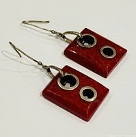 Top angle view of a pair of rectangular red coral earrings with two silver circular accents and silver hooks