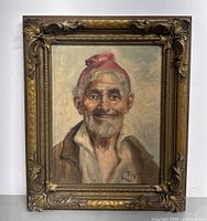 Full view of the framed portrait oil painting depicting an elderly man smiling with red headscarf, showing the complete artwork and ornate frame.
