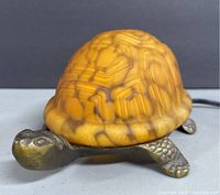 Side view of vintage turtle accent lamp showing glass shell and metal head and front legs