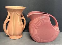 Front view photo of McCoy peach vase and pink Fiesta disk pitcher side by side on neutral surface with dark background