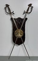 Full wall plaque with crossed fencing swords and brass shield mounted on wooden backboard