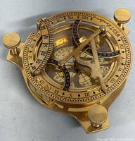 Close up of the vintage brass sundial compass showing Roman numerals and compass rose.