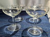 Four etched champagne coupes standing upright