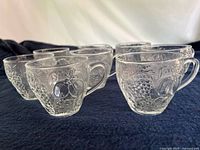 Eight matching clear embossed punch glasses on dark cloth