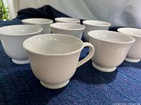 Eight matching white teacups grouped together