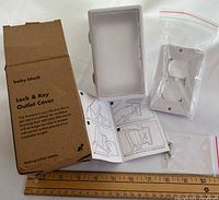 All components laid out: retail box, locking box, wall plate, key, screws, manual with ruler for scale