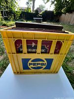 Front view of yellow Pepsi crate filled with records