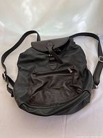 Front view of black leather backpack showing exterior zip pocket and adjustable straps