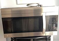 Front view showing stainless steel LG microwave on stand, full door, handle, control panel