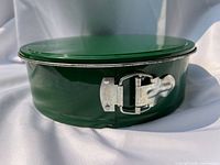 Side view of green springform pan, latch closed, lid on