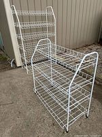 Both white collapsible wire shelves side by side outdoors