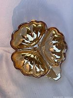 Top view of amber iridescent carnival glass dish showing three compartments and scalloped edges