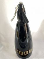 Front view of black soda syphon showing chrome head and gold square band
