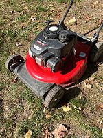 Full view of mower from front left showing deck, wheels, engine and handle