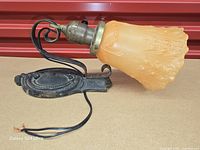 Side view of sconce showing amber glass shade, scroll arm, wiring