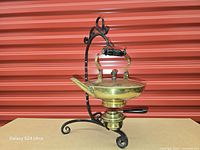 Full view of brass pot on wrought iron stand with burner