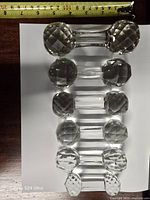 Six crystal knife rests aligned on white background with tape measure showing length