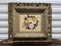Front view of ornate gilt frame with floral painting