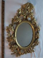 Front view showing ornate frame and mirror with ruler for scale