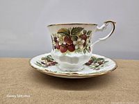 Side view of teacup on saucer showing floral pattern and gold trim