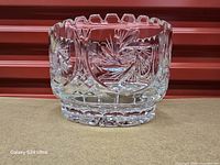 Front view shows heavy cut glass pinwheel pattern and scalloped rim